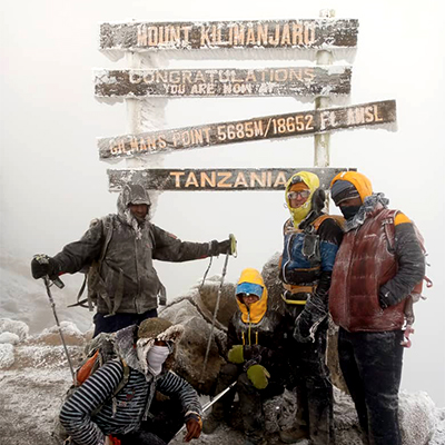 Clients celebrating at the summit of Mount Kilimanjaro, showcasing breathtaking views and triumphant smiles after their successful trek